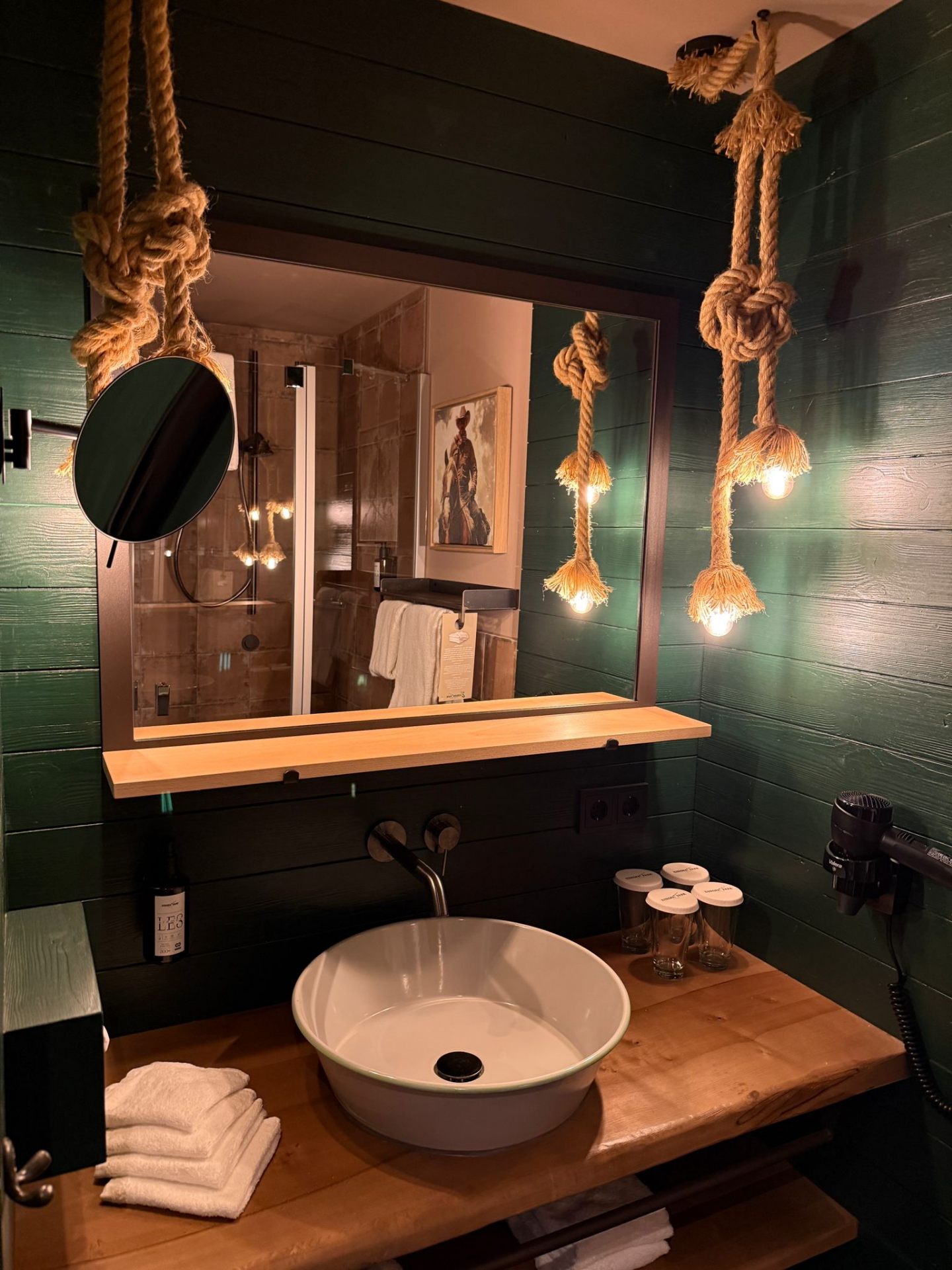 Riverside Lodge – Badezimmer mit Seil-Pendelleuchten und grüner Holzvertäfelung