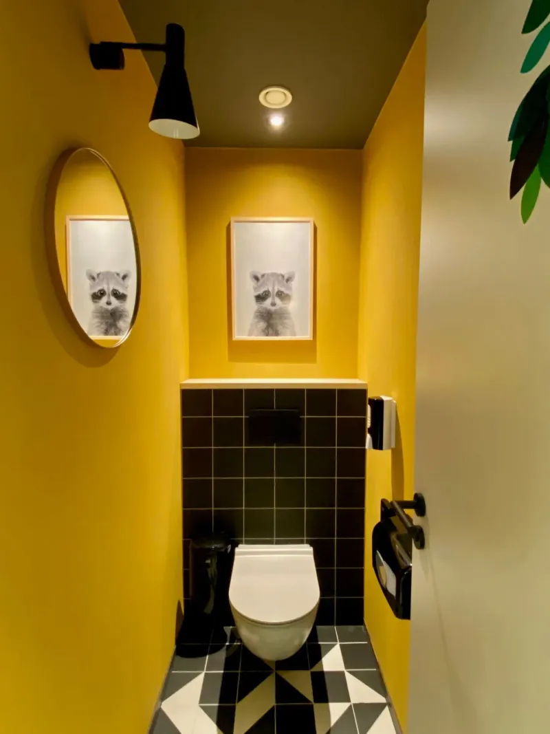 WC-Kabine in Gelb mit Waschbär-Motiv