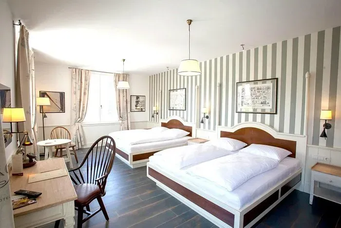 Mehrbettzimmer mit gestreifter Tapete und Holzbetten im maritimen Stil