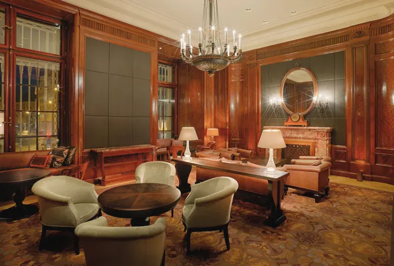 Salon mit Ledersesseln, Kronleuchter und Kamin